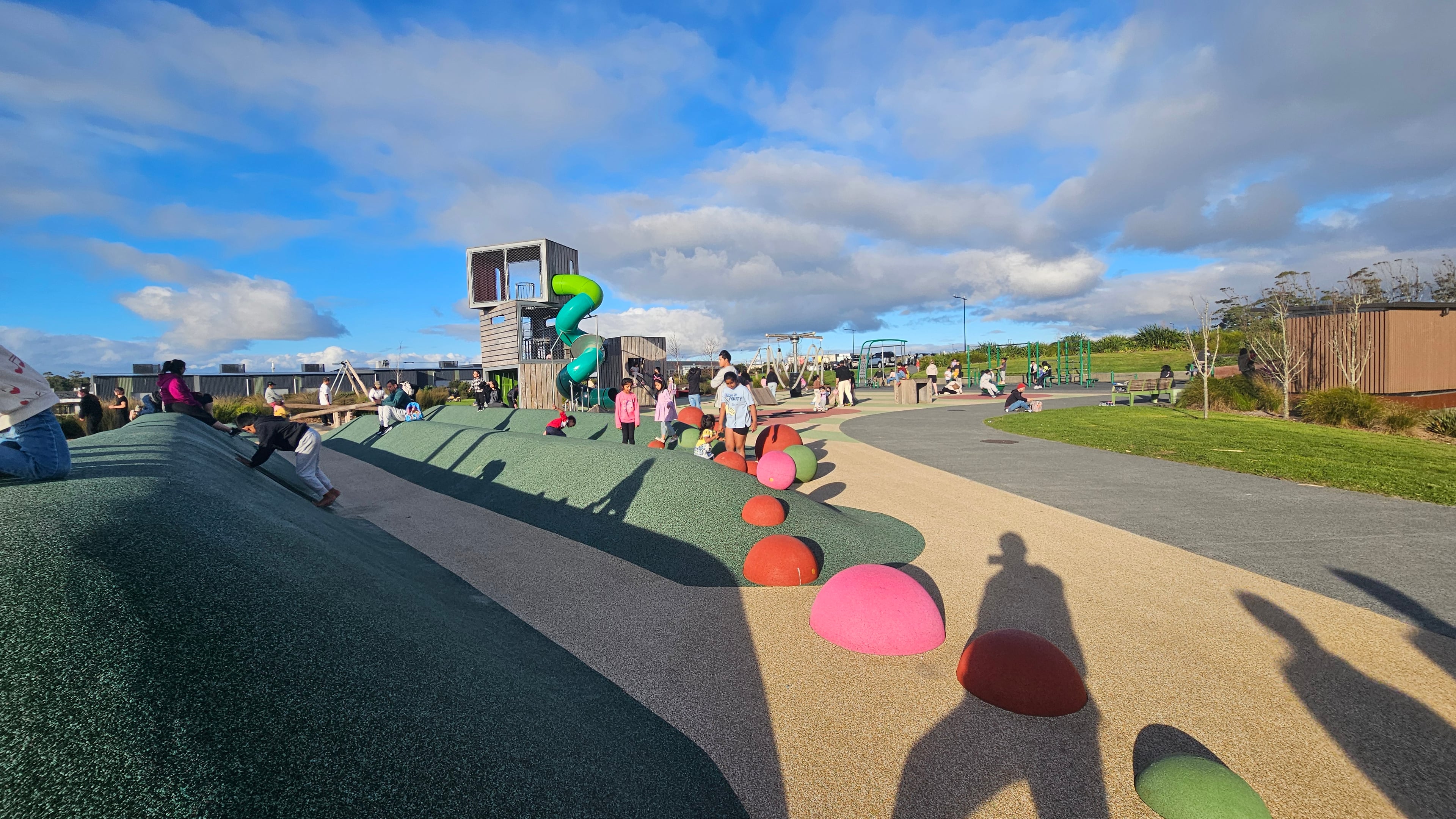 Younger-kids zone — green rubber climbing mound with tunnels underneath. Looks like my shadow made it into the photo too, haha.