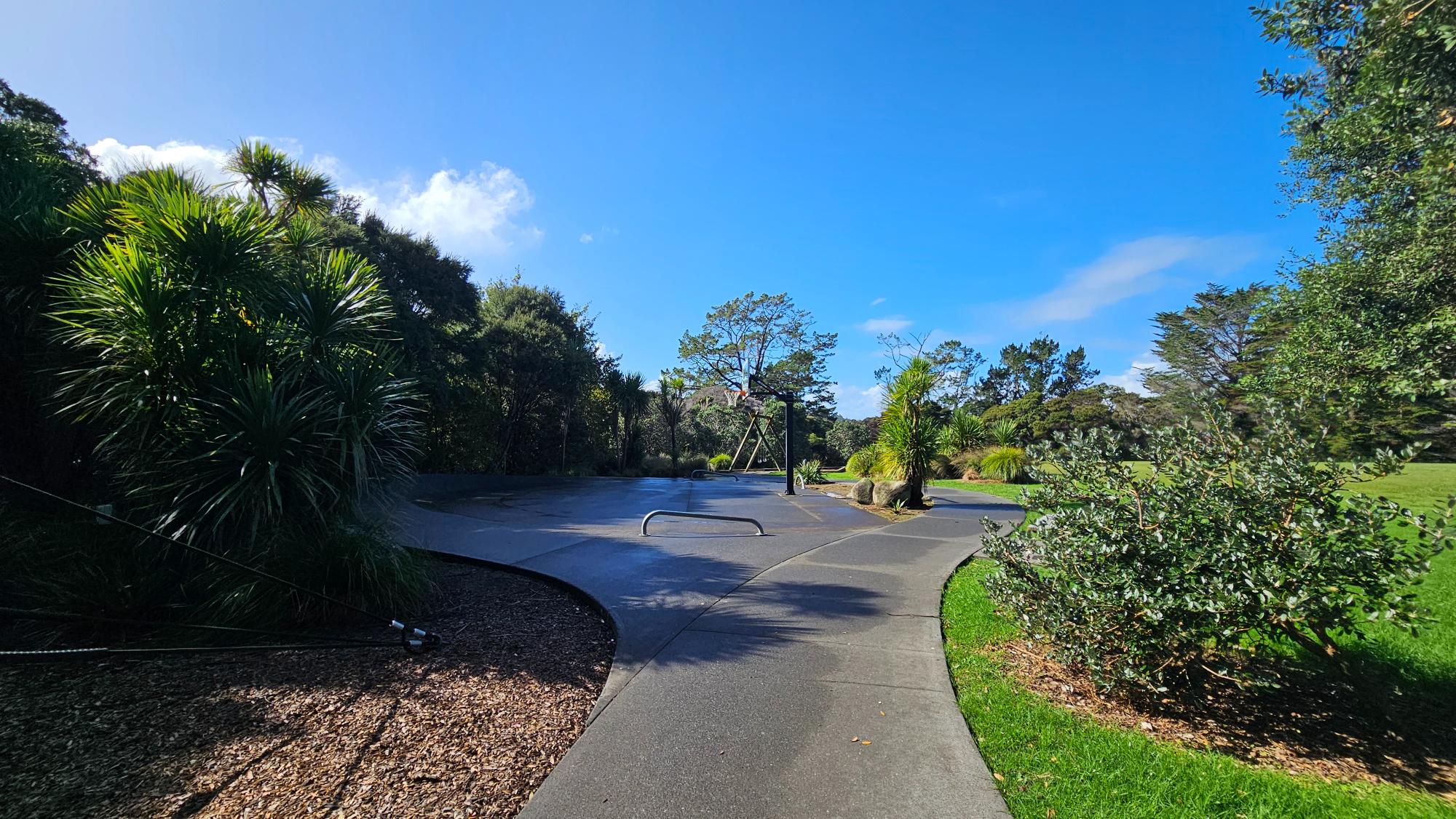 A basketball court and a paved path encircling the playground.