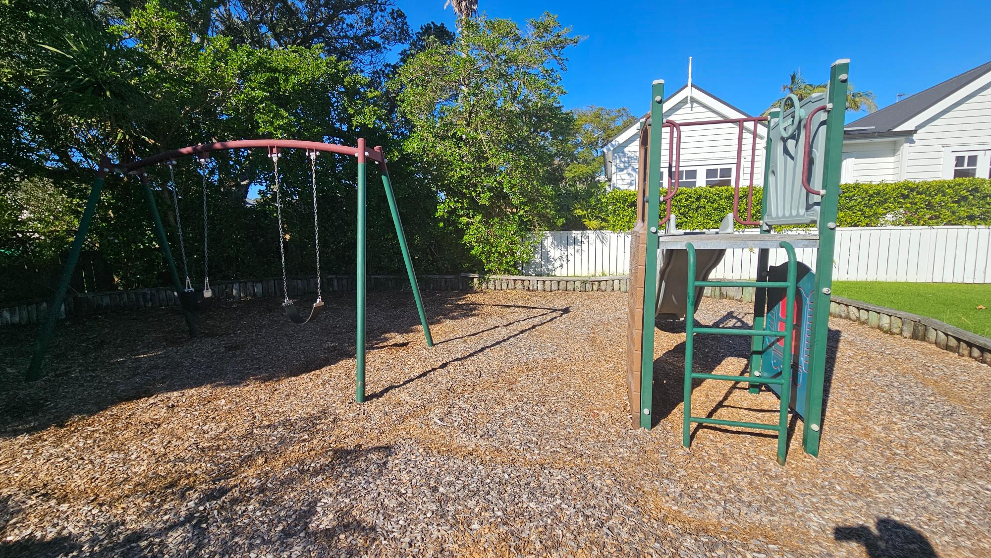 A small slide and swings at Kiwi Reserve Playground