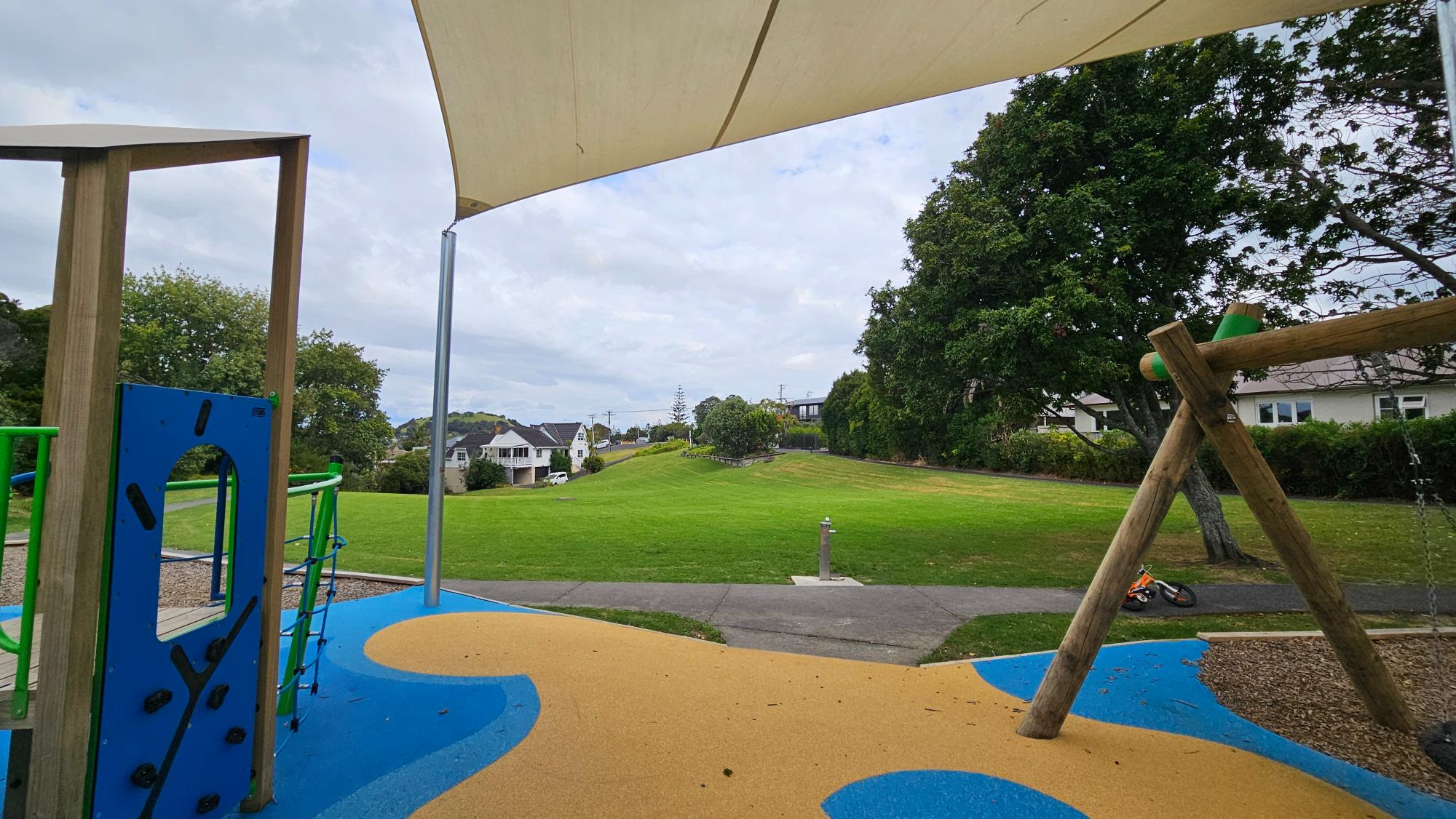 Open grass and reserve space beside Achilles Crescent playground for picnics and play