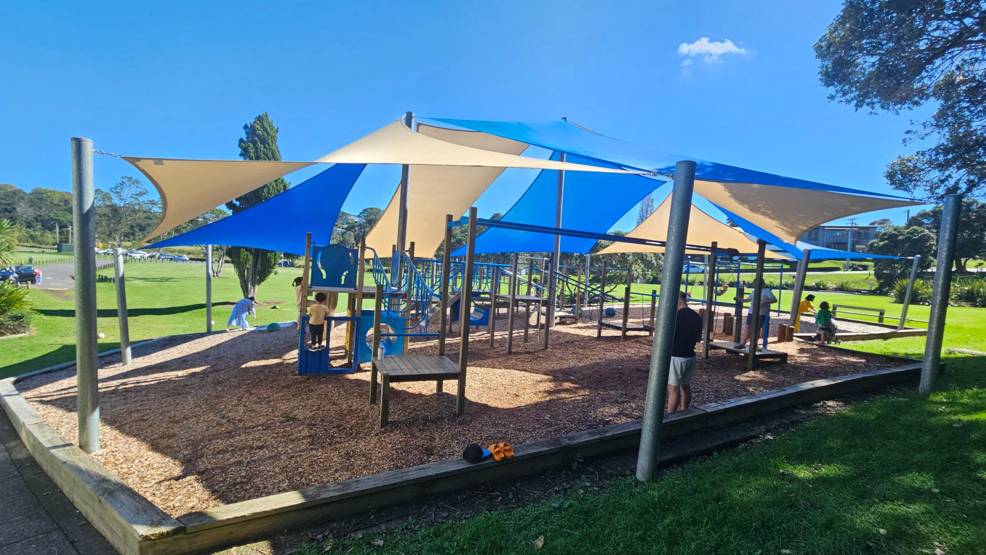 Shaded play structures and equipment at Little Shoal Bay Playground on Auckland's North Shore