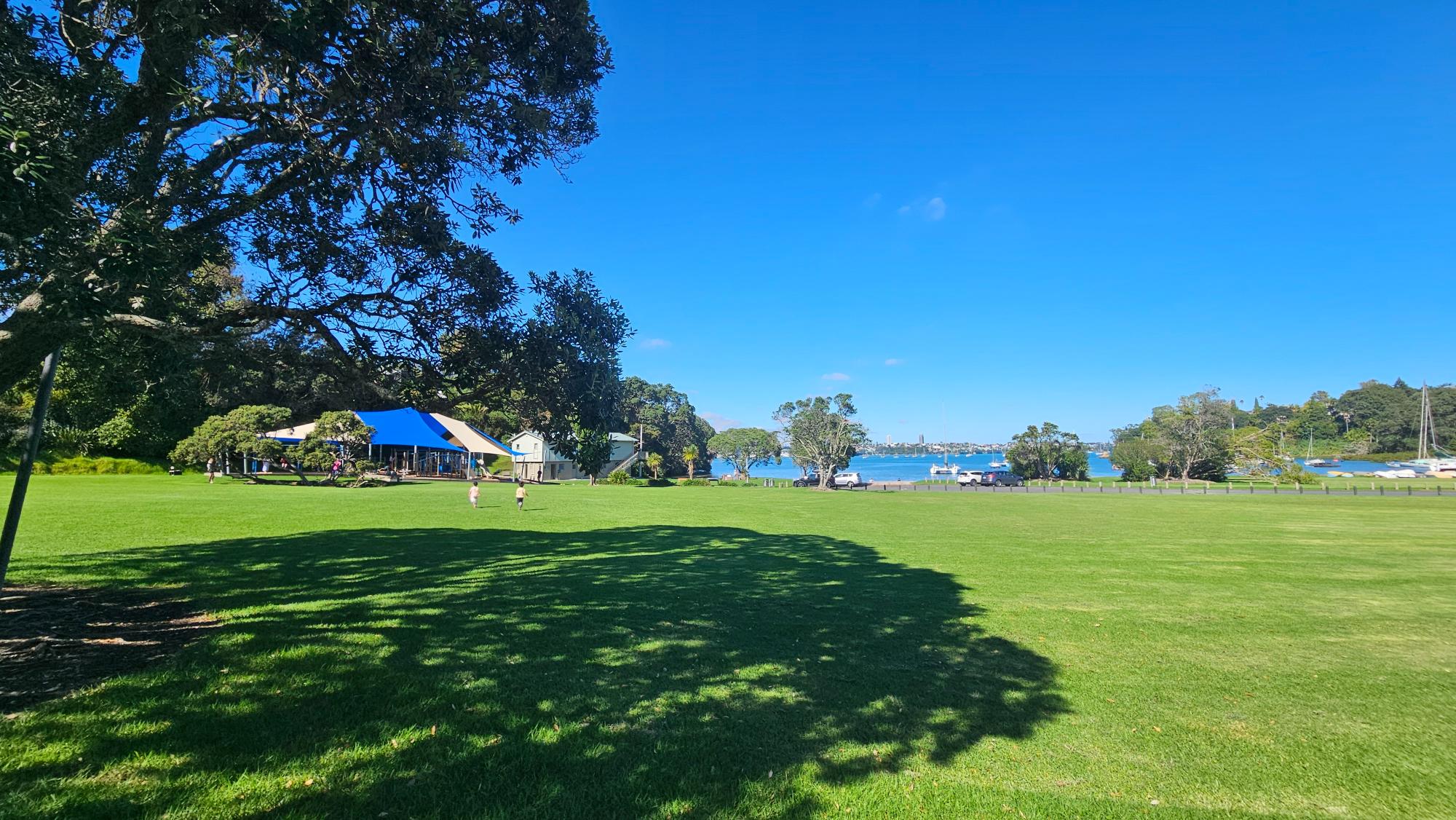 Open grass and family play space at Little Shoal Bay Playground beside the water