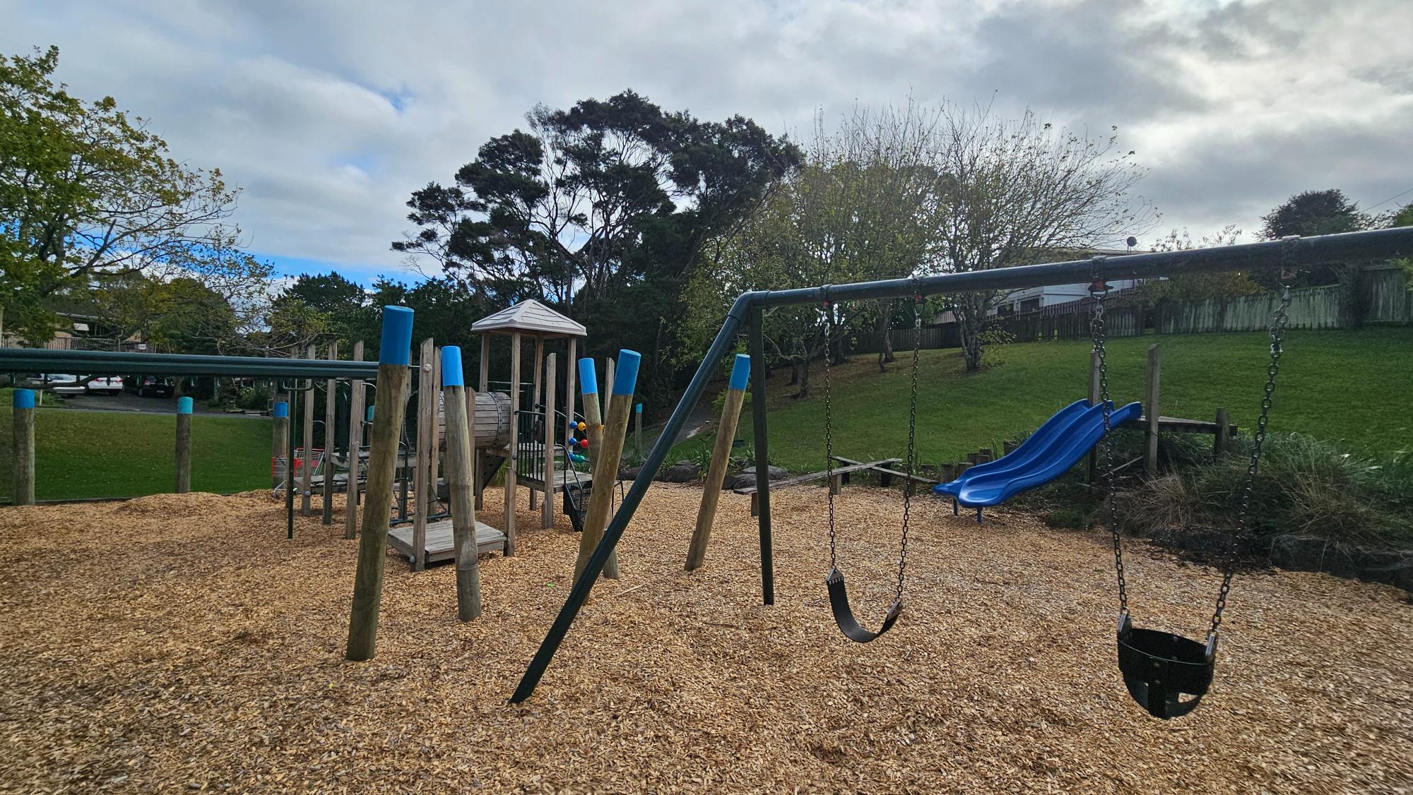 Swings, fort, slides, and wood chip surfacing at Lancelot Reserve Playground, Glenfield