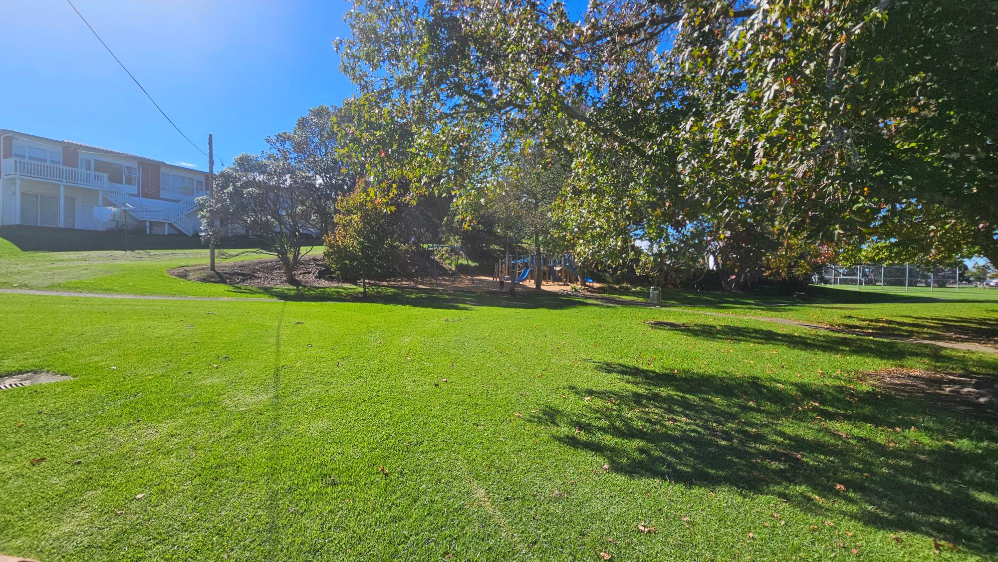 Play area and wide green lawns at Stafford Park, North Shore — open space for running, bikes, and picnics