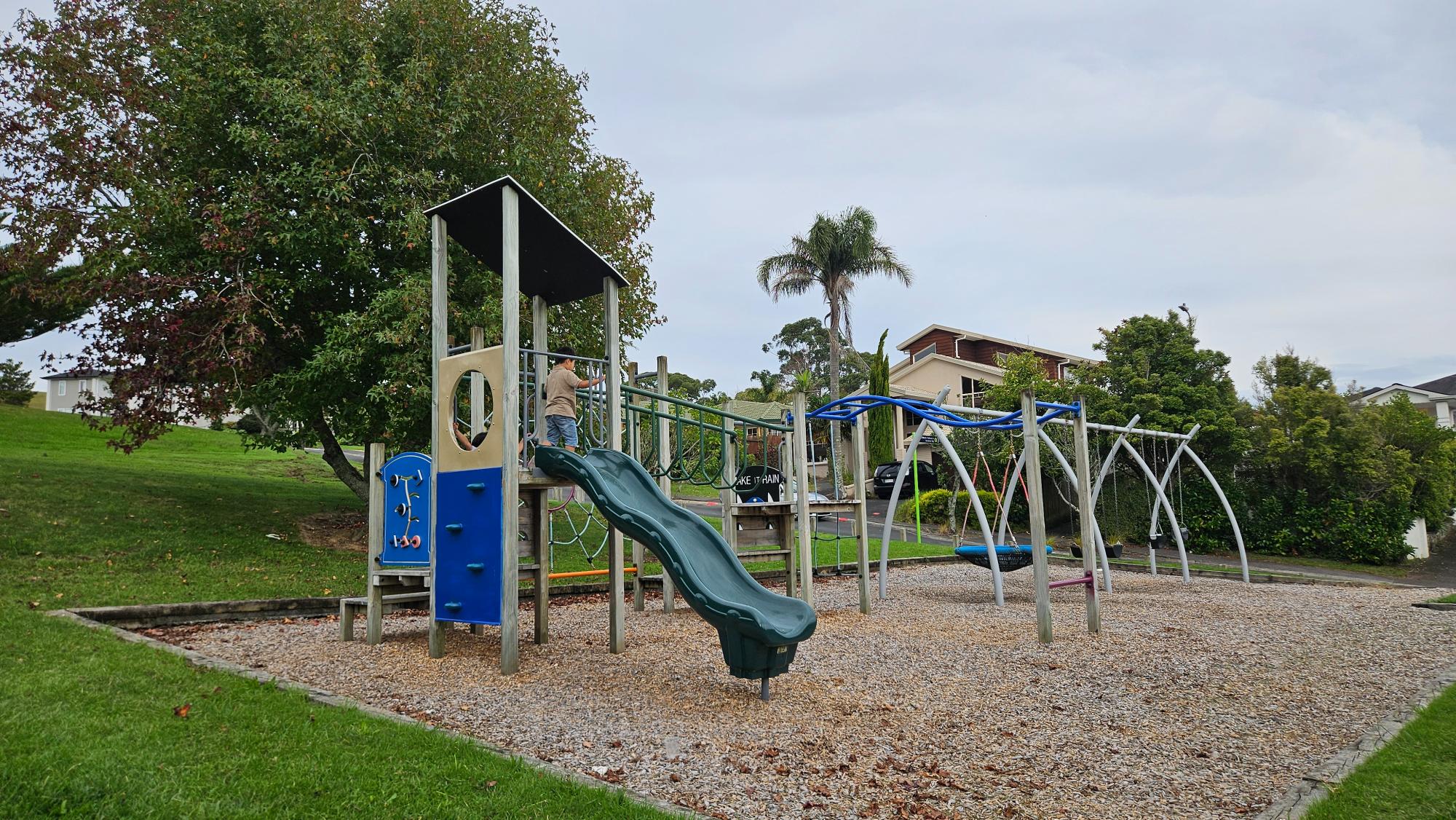 Swings and compact play equipment at Taroka Reserve, woodchip surface